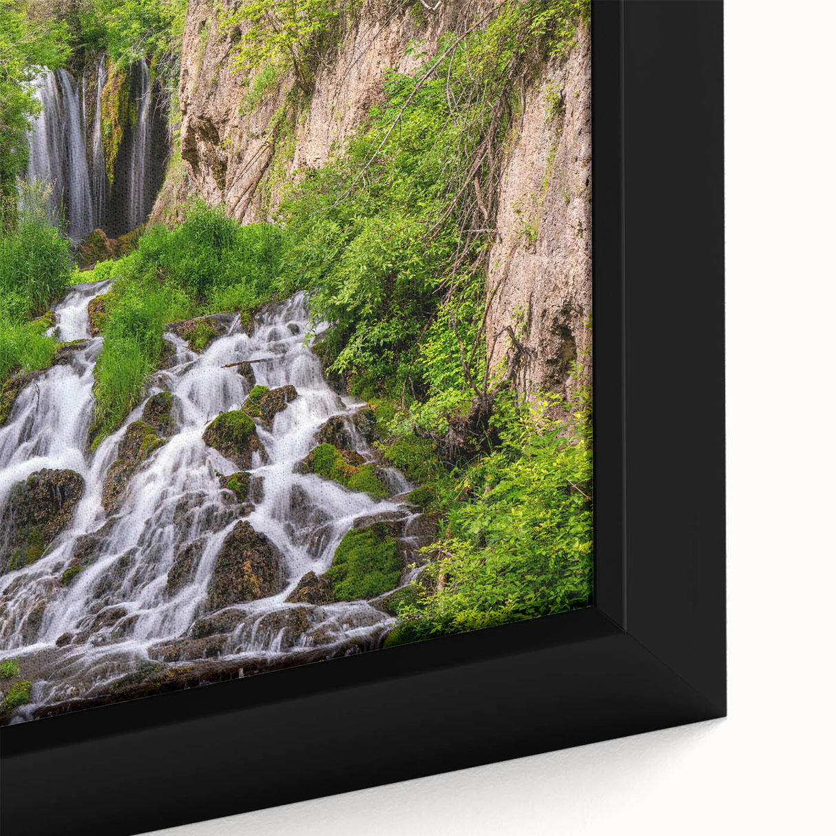 Close-up of a framed canvas artwork depicting a vibrant waterfall landscape, showcasing rich blues and greens, perfect for enhancing home decor with nature's beauty.