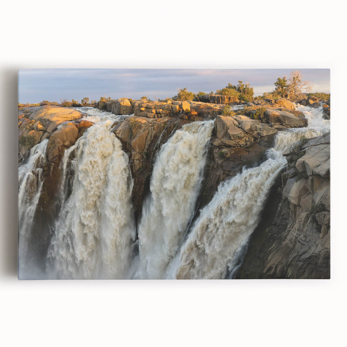 Stretched canvas artwork showcasing a serene landscape with a vibrant waterfall, surrounded by lush greenery and blue skies, ideal for home decor.