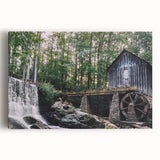 Stretched canvas wall art featuring a serene landscape with a picturesque watermill, lush greenery, and a tranquil river, perfect for home decor and nature enthusiasts.