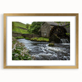 Framed wall art featuring a picturesque landscape of a serene watermill, highlighted with a gold frame and matting, perfect for enhancing home decor and interior design aesthetics.