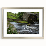 Framed wall art featuring a serene landscape of watermills, set in a silver frame with a mat, showcasing a peaceful nature scene ideal for home decor.