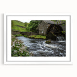 Framed landscape wall art featuring a serene watermill scene in soft pastel colors, presented in a sleek white frame with a mat for an elegant finish. Perfect for home decor.