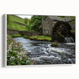 Framed canvas wall art depicting a serene watermill landscape with vibrant greenery, perfect for enhancing home decor. Side view showcases its elegant white frame and texture.