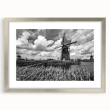 Framed wall art featuring a serene landscape with windmills, presented in a sleek silver frame with a mat, ideal for home decor and adding elegance to any space.