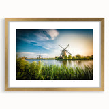 Elegant wall art featuring a serene landscape with windmills, framed in a gold mat. Ideal for adding sophistication to home decor, with soft, muted colors.