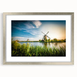 Framed wall art featuring a serene landscape with windmills, showcasing a silver mat and frame, ideal for home or office decoration. Perfect blend of nature and art.