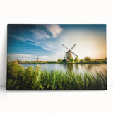 Stretched canvas wall art featuring a serene landscape with windmills against a vibrant sunset, showcasing rich colors and tranquil scenery, perfect for home decor.