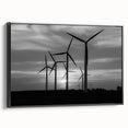 Framed canvas wall art featuring a serene landscape with windmills, set against a vibrant sunset. The artwork is displayed in a sleek black frame, adding elegance to any room decor.