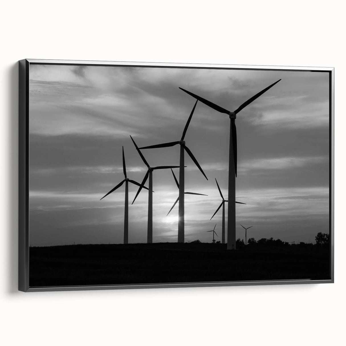 Framed canvas wall art featuring a serene landscape with windmills, set against a vibrant sunset. The artwork is displayed in a sleek black frame, adding elegance to any room decor.