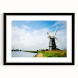Black-framed wall art featuring a serene landscape with windmills, ideal for home decor, displaying a tranquil countryside scene in vibrant hues. Perfect for adding a touch of nature to any room.