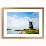 Framed wall art featuring a serene landscape with windmills, set against a golden mat, ideal for home decor. The elegant design enhances any room's aesthetic.