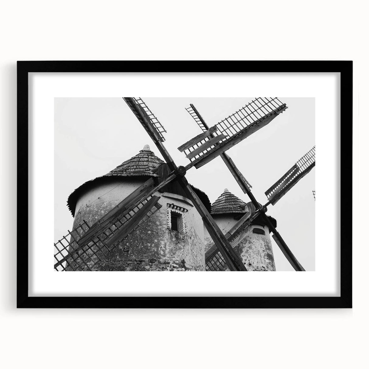 Framed wall art featuring a serene landscape with windmills, showcased in a sleek black frame with matting, perfect for enhancing modern home decor.