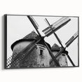 Framed canvas wall art depicting a serene landscape with windmills under a sunset sky, featuring a sleek black frame, ideal for modern home décor.
