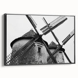 Framed canvas wall art depicting a serene landscape with windmills under a sunset sky, featuring a sleek black frame, ideal for modern home décor.