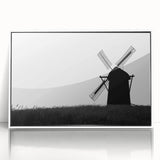 Framed acrylic wall art featuring a serene landscape with windmills, set against a vibrant sunset. The artwork is displayed in a white frame, enhancing its elegant design and perfect for modern home decor.