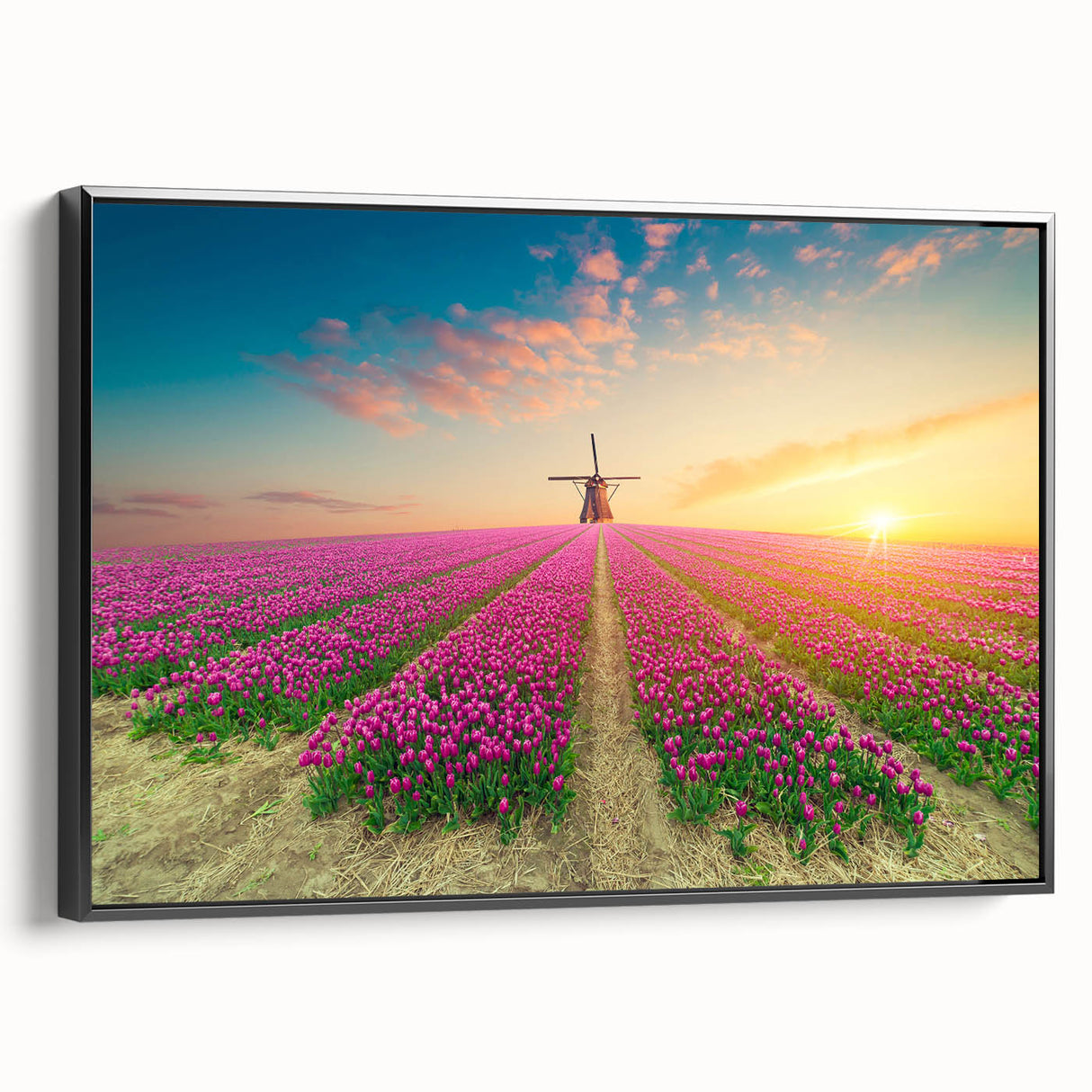 Framed canvas wall art featuring a serene landscape with windmills, showcasing a vibrant sunset scene. The artwork is presented in a sleek black frame, adding a modern touch to home decor. Ideal for enhancing living spaces with its calming colors and natural elements.