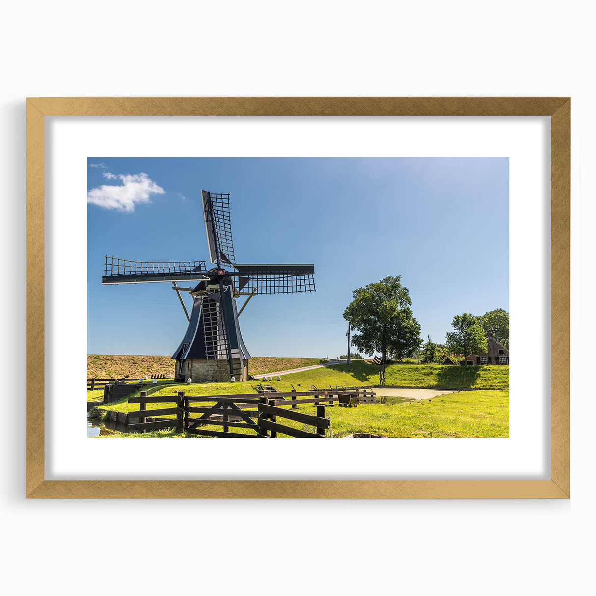 Framed wall art featuring a serene landscape with windmills, presented in a gold frame with a mat. Ideal for home decor, showcasing warm colors and tranquil scenery.