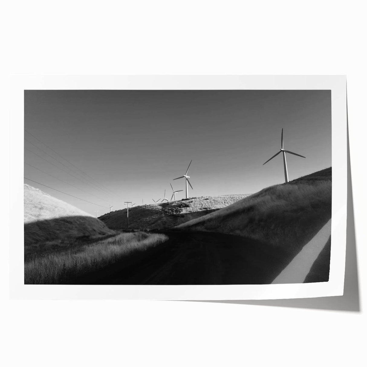 A rolled print showcasing a vibrant landscape with windmills against a sunset backdrop, perfect for home decor and wall art enthusiasts. This high-quality design adds a serene touch to any living space and is ideal for artistic interior styling.