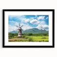 Framed wall art featuring a serene landscape with windmills, showcasing a vibrant blue sky and lush greenery. The black frame enhances the design, perfect for home decor.