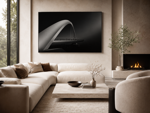 Luxury modern living room featuring a black-and-white architectural bridge wall art print above a cream sectional sofa, styled with neutral décor, stone accents, and warm natural light.
