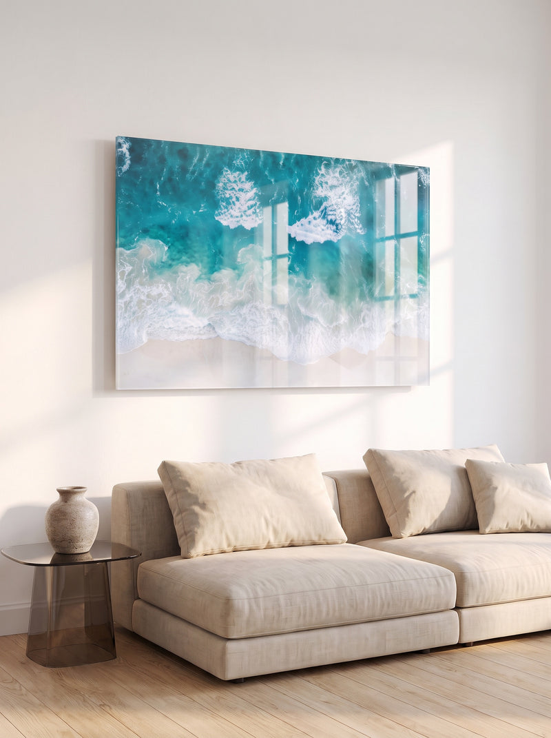 Large acrylic print of turquoise ocean waves hanging close to the wall above a linen sofa