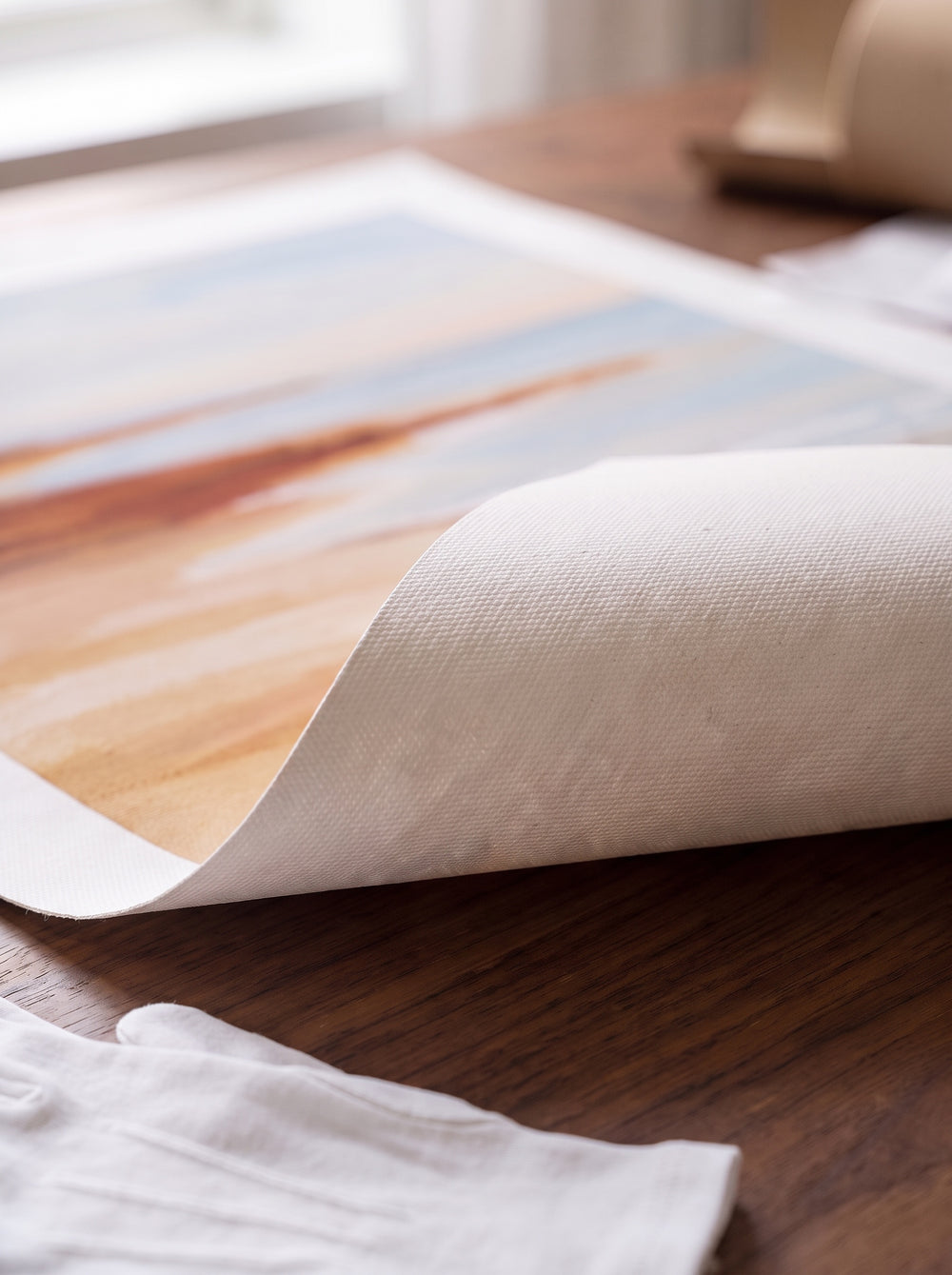 Close-up of a rolled canvas print corner lifted to show the plain unprinted canvas back