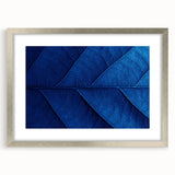 Textured abstract art print depicting floral designs in soft pastel shades, framed in silver, ideal for bedroom ambiance.