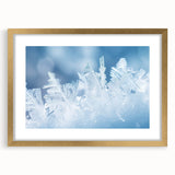 Textured art print of abstract frost patterns in muted white and gray, framed in gold, ideal for bedroom art.