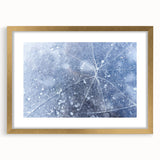 Textured art depicting abstract frost patterns in muted white and blue tones, framed in gold, ideal for bedroom wall decor.