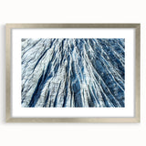 Abstract art print featuring close-up of frost patterns in muted blue and gray, silver-framed with mat.