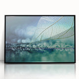 Large abstract wall art featuring close-up leaves in muted green tones, framed in black acrylic.