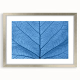 Textured art print of abstract leaves in muted green and silver, framed with a mat, ideal for bedroom wall decor.