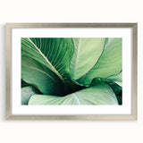 Close-up textured art of abstract leaf designs in green and brown, framed in silver, ideal for bedroom art.