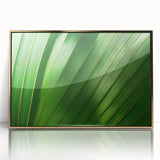 Large art print of close-up leaves in vibrant green tones, framed in gold acrylic, reflecting mid-century modernist style.