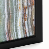Close-up of black wall art featuring colorful, textured natural elements on a framed canvas.