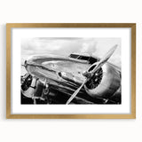 Abstract art print of a stylized airplane in gold and black tones on a framed canvas.
