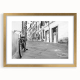 Abstract art print of a stylized bicycle in gold and black tones, framed with mat, suitable for bedroom or dining room decor.