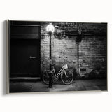 Framed canvas featuring a vintage poster of a black bicycle against a colorful, abstract landscape background.