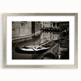 Abstract art print of a gondola on water in muted blue and gray tones, framed in silver, ideal for dining room decor.