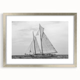 Abstract art print of a sailboat in muted blue and white tones on a silver-framed canvas.