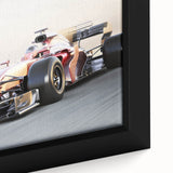 Framed canvas of vividly colored race cars in motion on a textured black background.