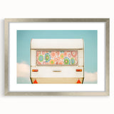 Abstract art print of a colorful caravan in pastels on a silver-framed mat, ideal for dining room decor.