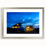 Abstract art print of a stylized caravan in muted earth tones, framed in silver, suitable for dining room decor.