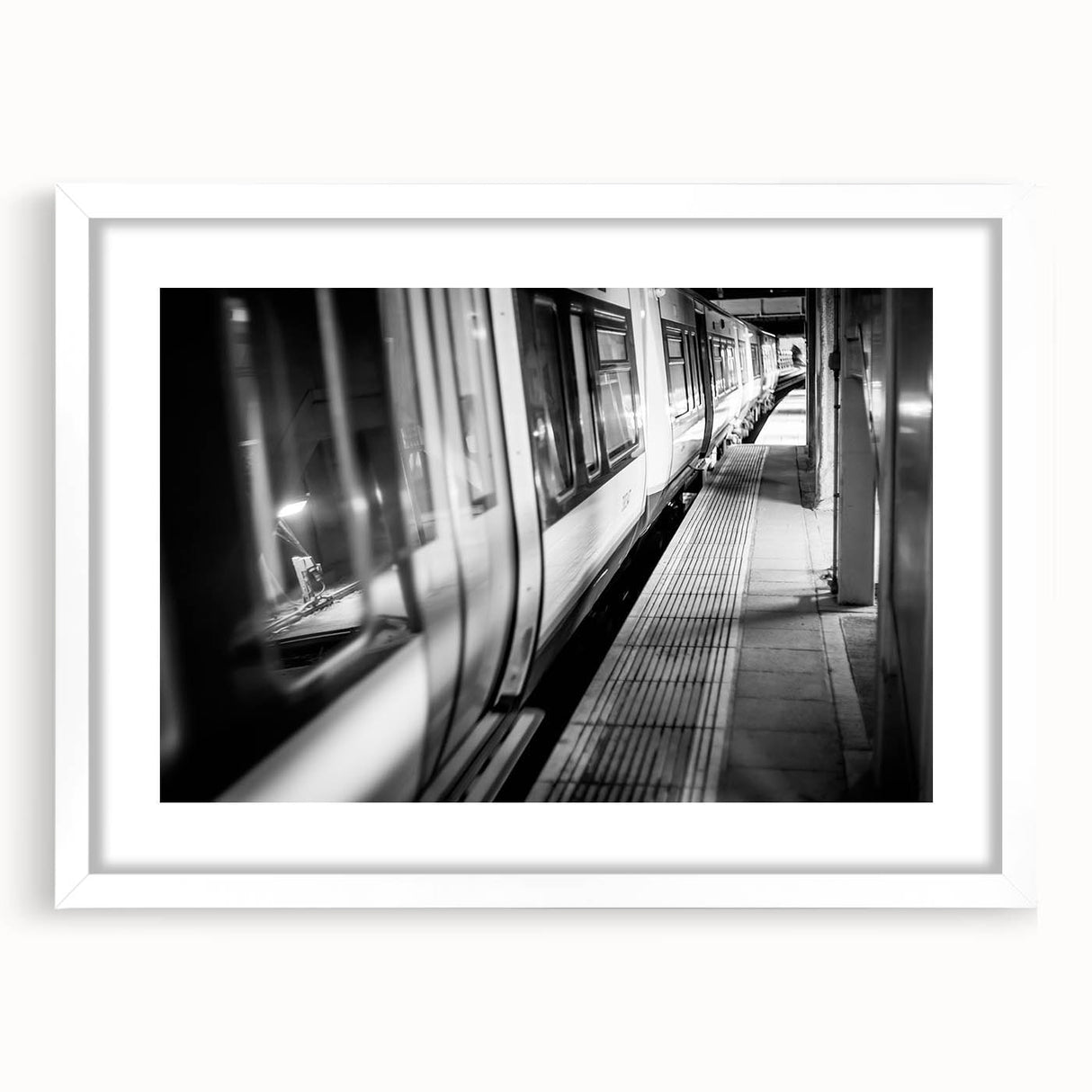 Abstract art print of a stylized train in muted gray and blue tones, framed with a white mat.