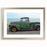 Textured art print of abstract trucks in muted gray and blue tones, framed in silver, ideal for modern bedroom decor.
